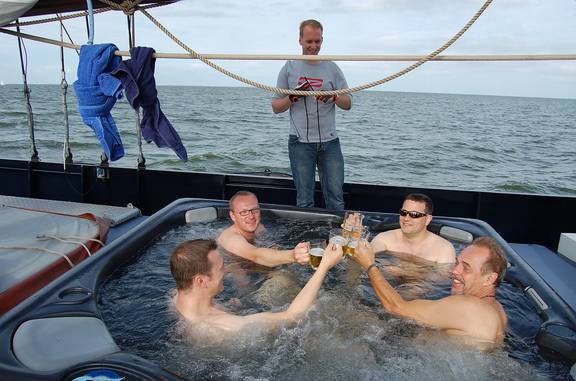 Guests raising a toast in the hot tub on the deck of the Mare fan Fryslân