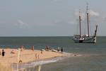 Two-masted clipper Mars beside a sandbank with swimmers in the Wadden Sea