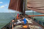 Guests relaxing on the deck of the Medusa beneath brown sails