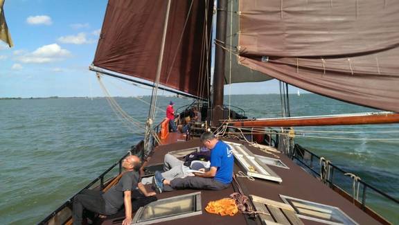 Guests relaxing on the deck of the Medusa beneath brown sails