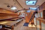 Overview of the saloon of the Medusa with wooden tables and skylights