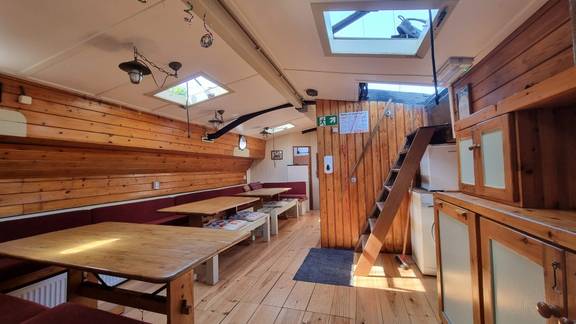 Overview of the saloon of the Medusa with wooden tables and skylights