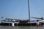 Tjalk Nieuwe Zorg resting on the tidal flats with guests beside the ship