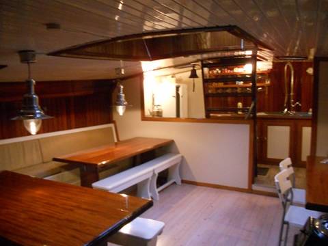 Wooden dining tables and benches in the saloon of the Nieuwe Zorg