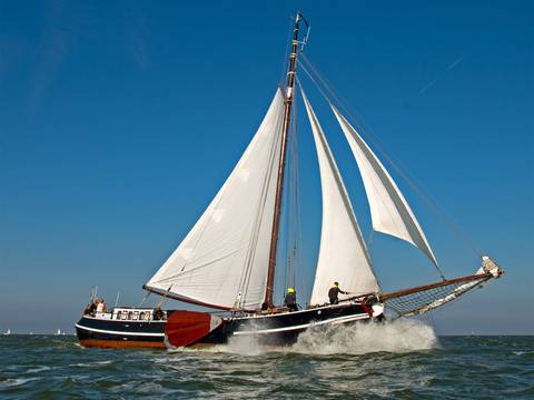 Tjalk Orion under white sails on the water