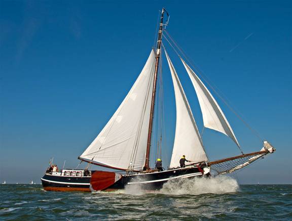 Tjalk Orion under white sails on the water