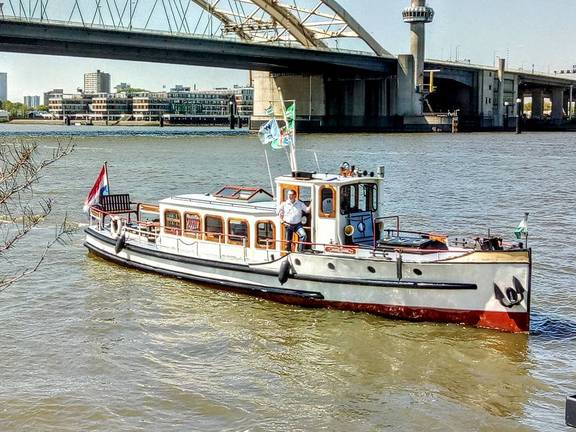 Saloon boat Oude Maze cruising beside a bridge in Rotterdam