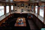 Wood-panelled saloon with benches and tables aboard the Oude Maze