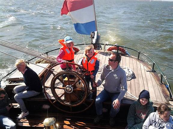 Guests at the wheel on the aft deck of the Pelikaan