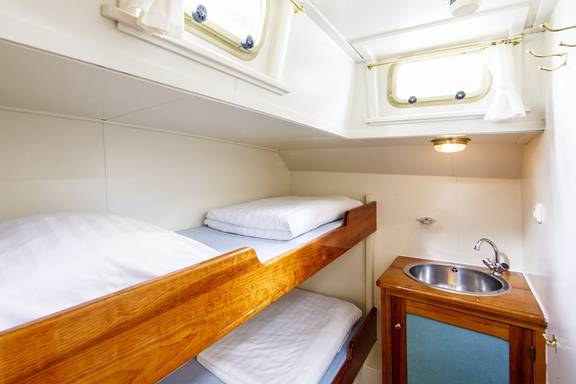 Bright cabin with a bunk bed and washbasin on the Pelikaan