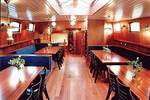 Saloon of the Poseidon with wooden dining tables and blue benches