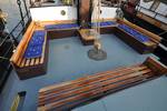 Wooden benches with blue cushions in the deck seating area of the Poseidon