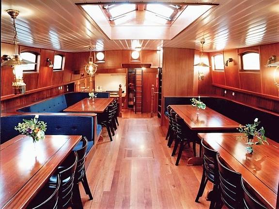 Saloon of the Poseidon with wooden dining tables and blue benches