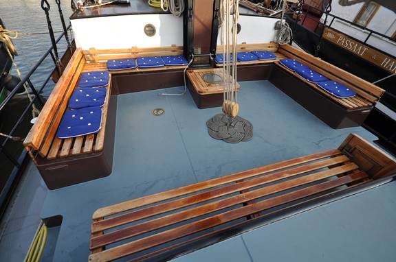 Wooden benches with blue cushions in the deck seating area of the Poseidon
