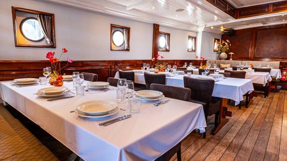Dining room of the Simmer fan Fryslân with set tables and portholes