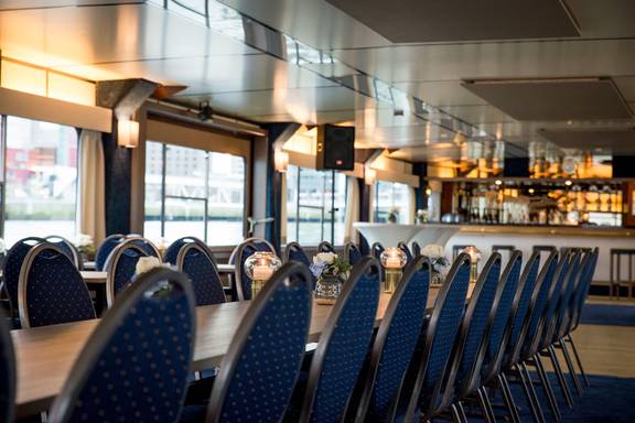 Long meeting table with blue chairs in the saloon of the Smaragd 2