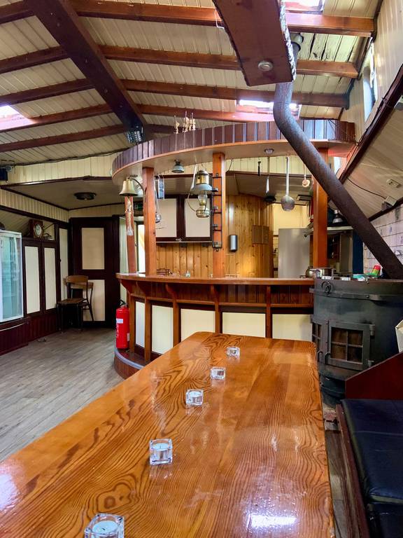 Wooden dining table and bar in the saloon of the Spartivento