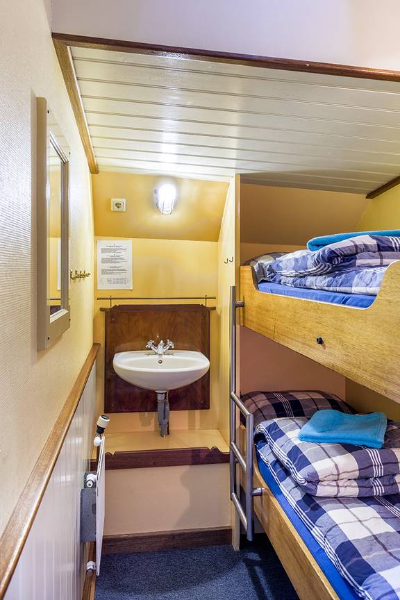 Twin-berth cabin with a bunk bed and washbasin on the Spes Mea