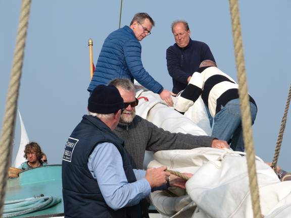 Guests folding a sail together aboard the Spes Mea