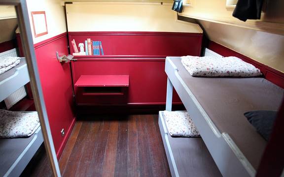 Cabin of the Sybaris with bunk beds and a red bench