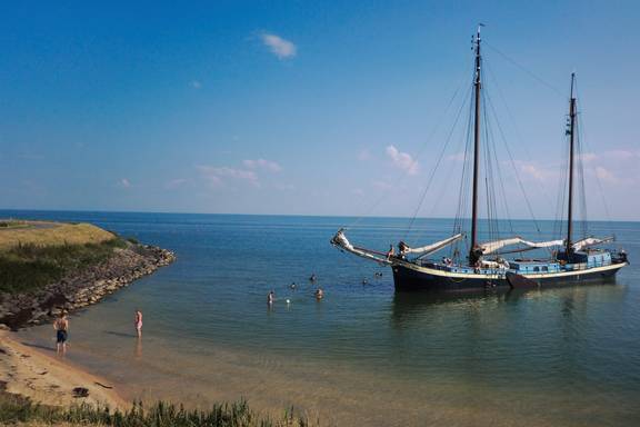 Sybaris at anchor beside a sandy shore