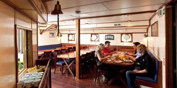 Guests at the dining tables in the wood-panelled saloon of the Thalassa