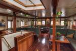 Wood-panelled saloon of the Thalassa with tables and green benches