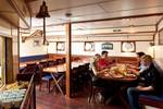 Guests at the dining tables in the wood-panelled saloon of the Thalassa