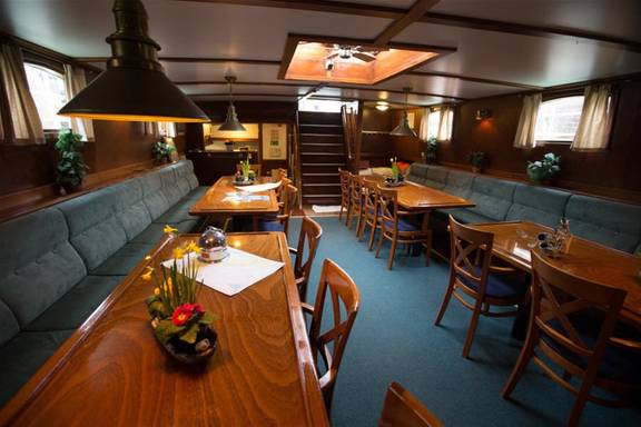 Saloon of the Utopia with wooden dining tables and green benches