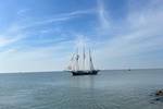 Three-masted Vrijheid sailing on calm water along the coast