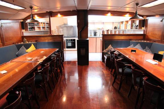 Saloon of the Vrijheid with long wooden dining tables and benches