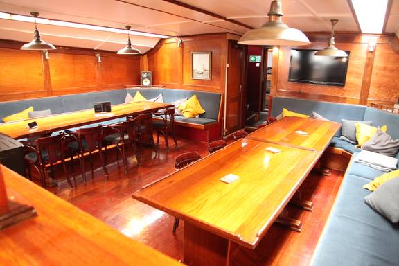 Saloon of the Vrijheid with wooden dining tables and benches