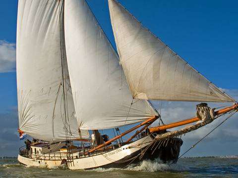 De Vrouw Dina under white sails, viewed diagonally from the bow