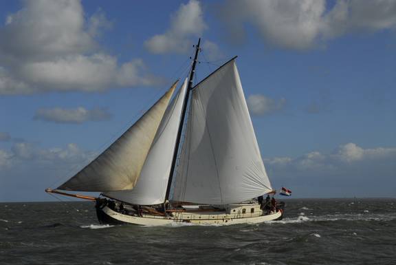 De Vrouw Dina under white sails, viewed from the side