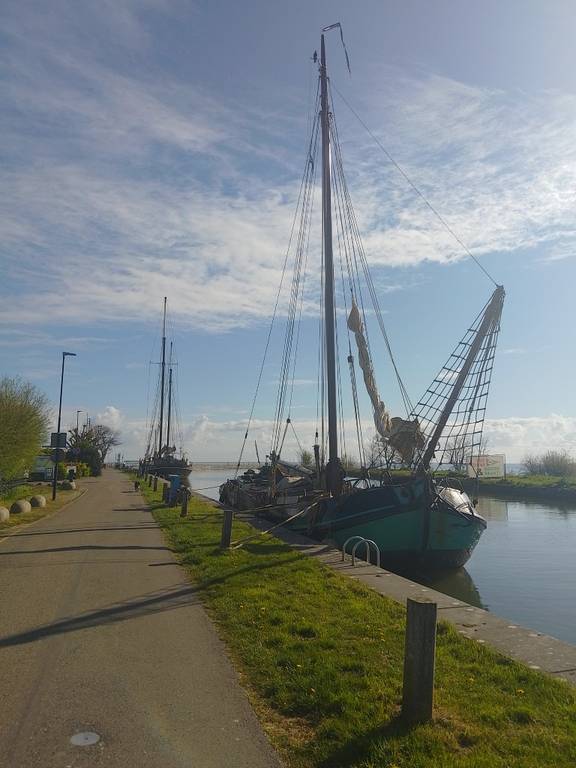 Tjalk Vrouwe Jitske moored beside a green riverbank