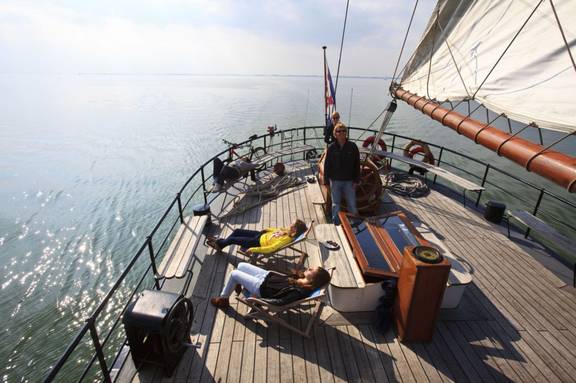Guests relaxing on the deck of 't Wapen fan Fryslân while sailing