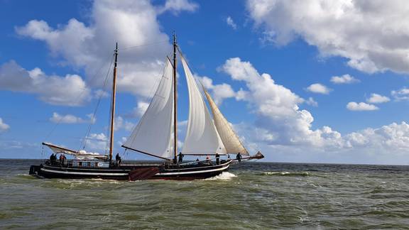Clipper Waterman under white sails beneath a blue sky with clouds