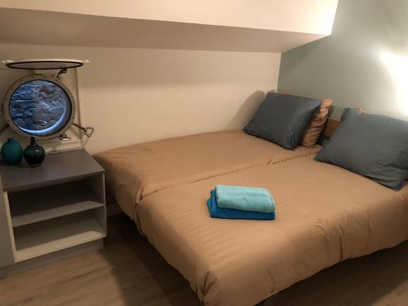 Cabin of the Wilhelmina with a double bed and round portholes