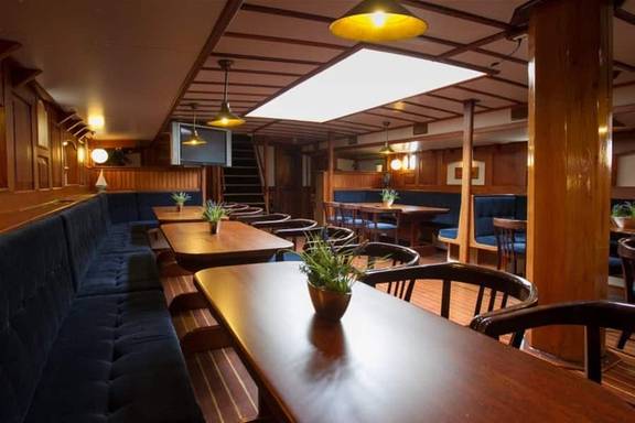Dining tables in the wood-panelled saloon of the Willem Barentsz