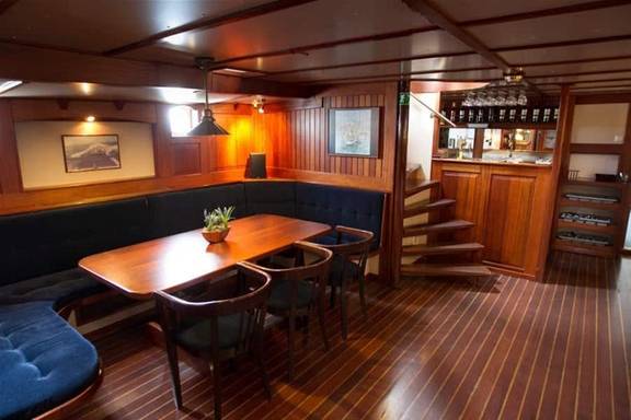 Seating area with a wooden table in the saloon of the Willem Barentsz