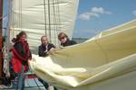 Guests folding a sail together on the deck of the Gulden Belofte