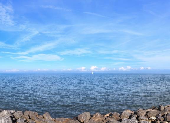 View across the IJsselmeer along a rocky shore and a lighthouse
