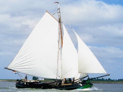 Tjalk Vrouwe Jitske under white sails on the water