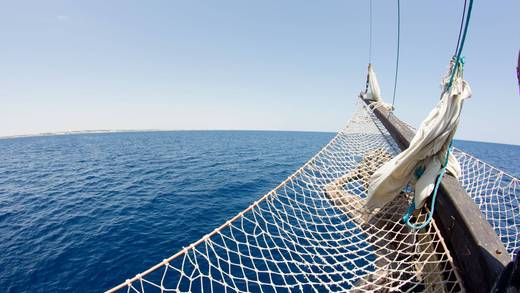 Bowsprit and net of a sailing ship above a blue sea