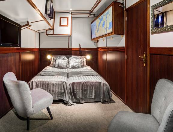 Cabin with a double bed and armchairs on the Mare fan Fryslân