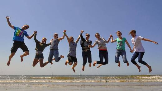 School pupils jumping together on the exposed tidal flats