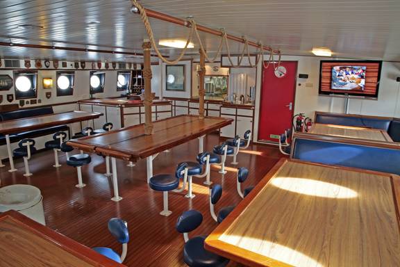 Wooden dining tables in the spacious saloon of the Eendracht