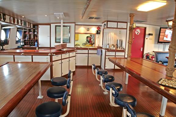 Saloon of the Eendracht with long wooden tables and fixed stools