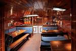 Wood-panelled saloon of the Orion with dining tables and blue benches