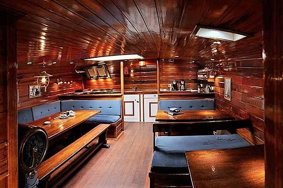 Wood-panelled saloon of the Orion with dining tables and blue benches